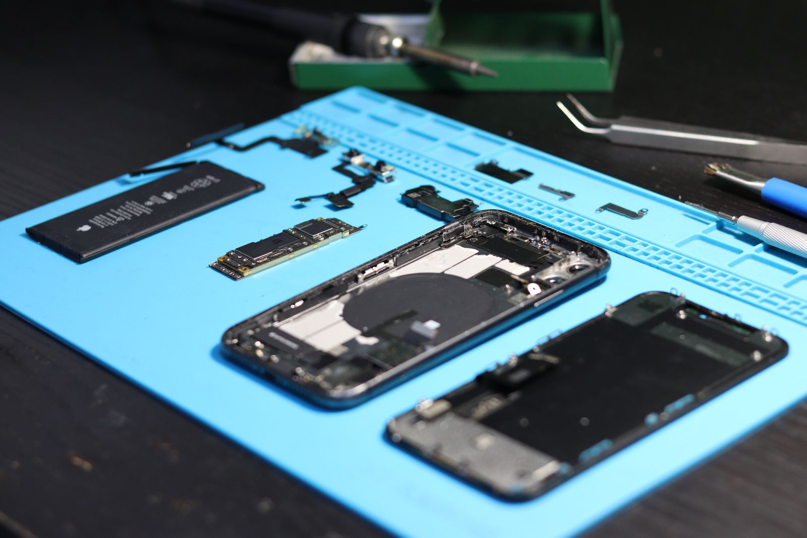 Rozebraný iPhone, baterie a skutečná základní deska na servisním stole